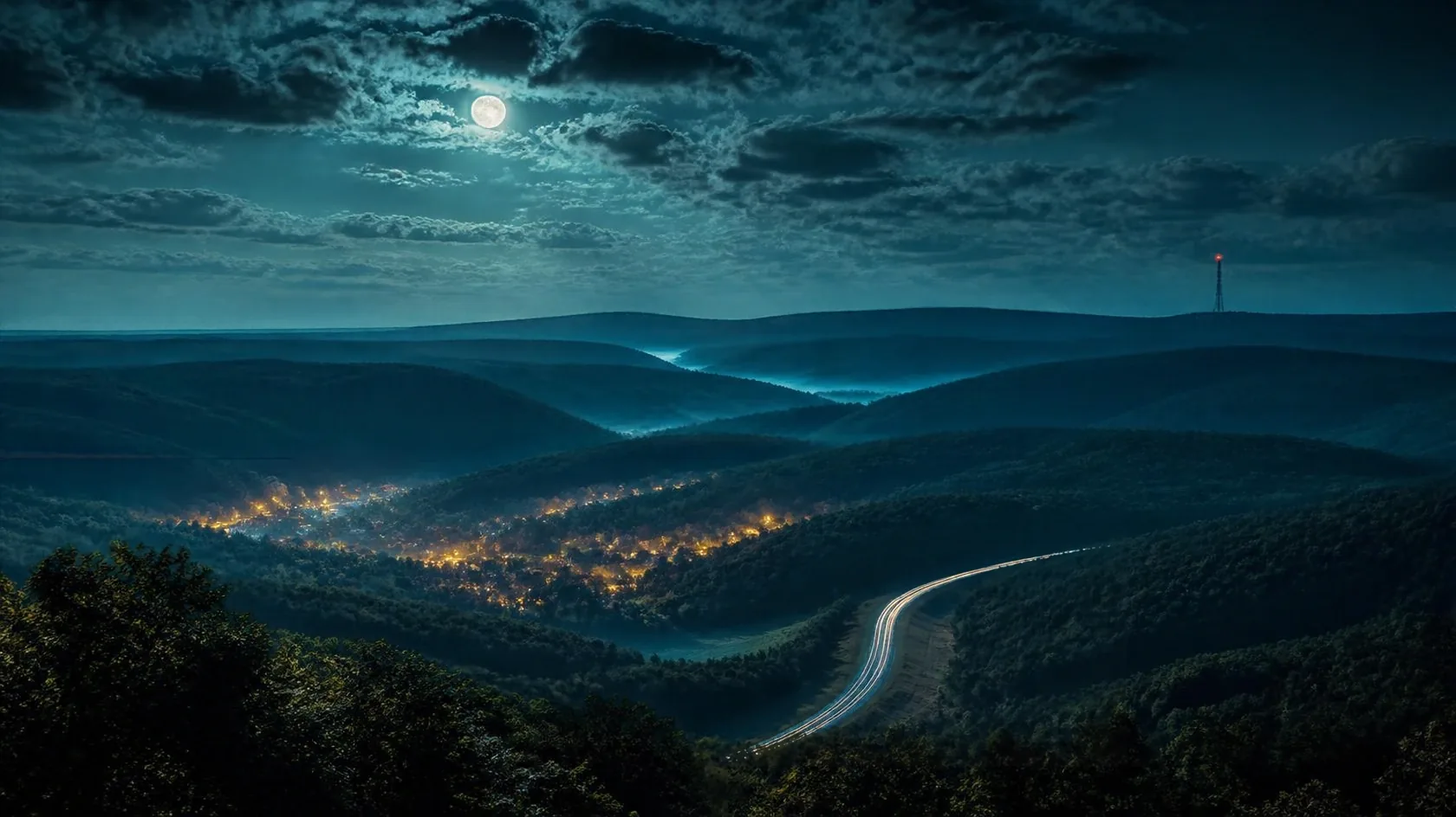 The Ozark hills at night under a moonlit sky. Forested ridges fold into the distance, a small town glows amber in the valley, a highway winds through with headlight trails, and a radio tower blinks red on a far ridge.